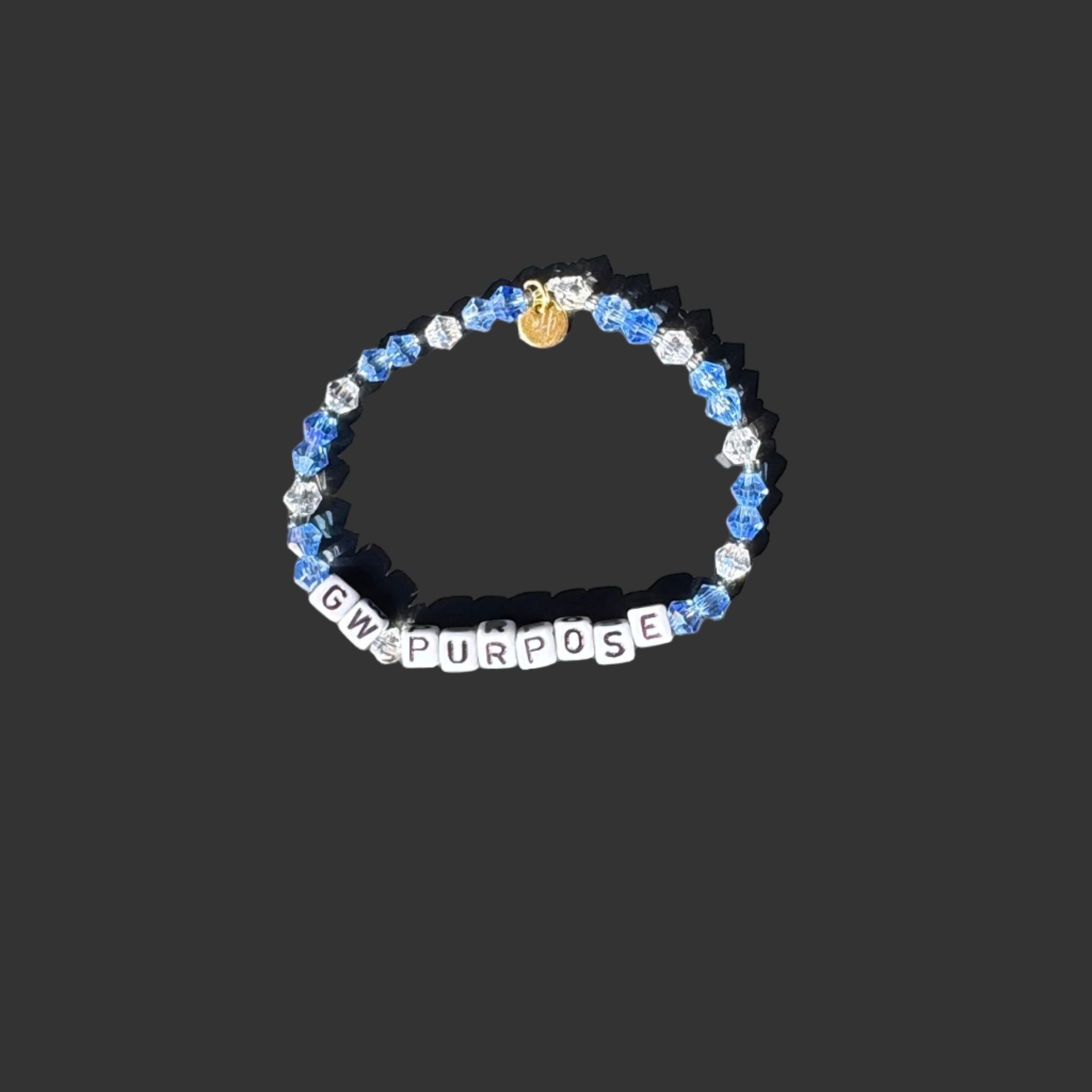 Bracelet with letters and a small yellow charm on a black surface